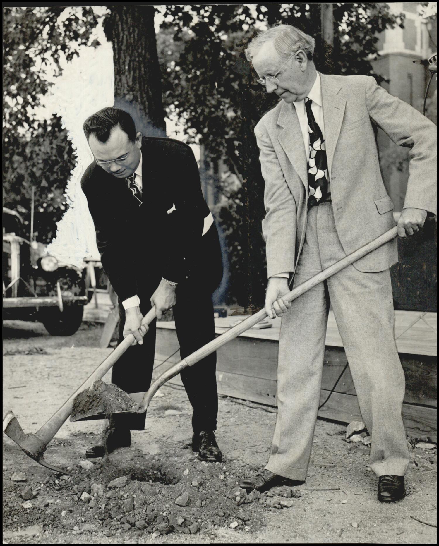 Two men in suits break ground with a shovel and a pickaxe at the June 1948 groundbreaking ceremony for the Baptist Building
