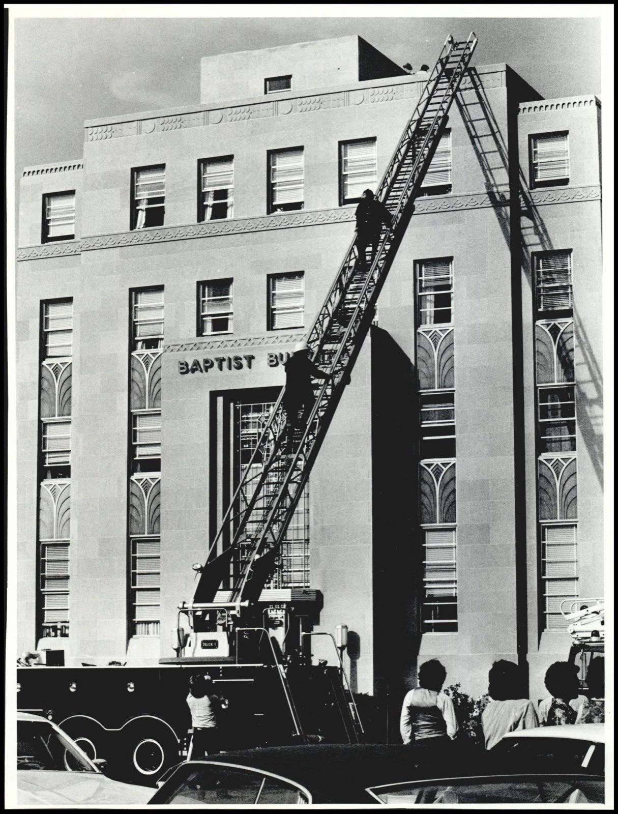 September 1979: a fire department ladder truck raised against the BAPTIST BUILDING facade, firefighters climbing toward the roof as onlookers watch from the street