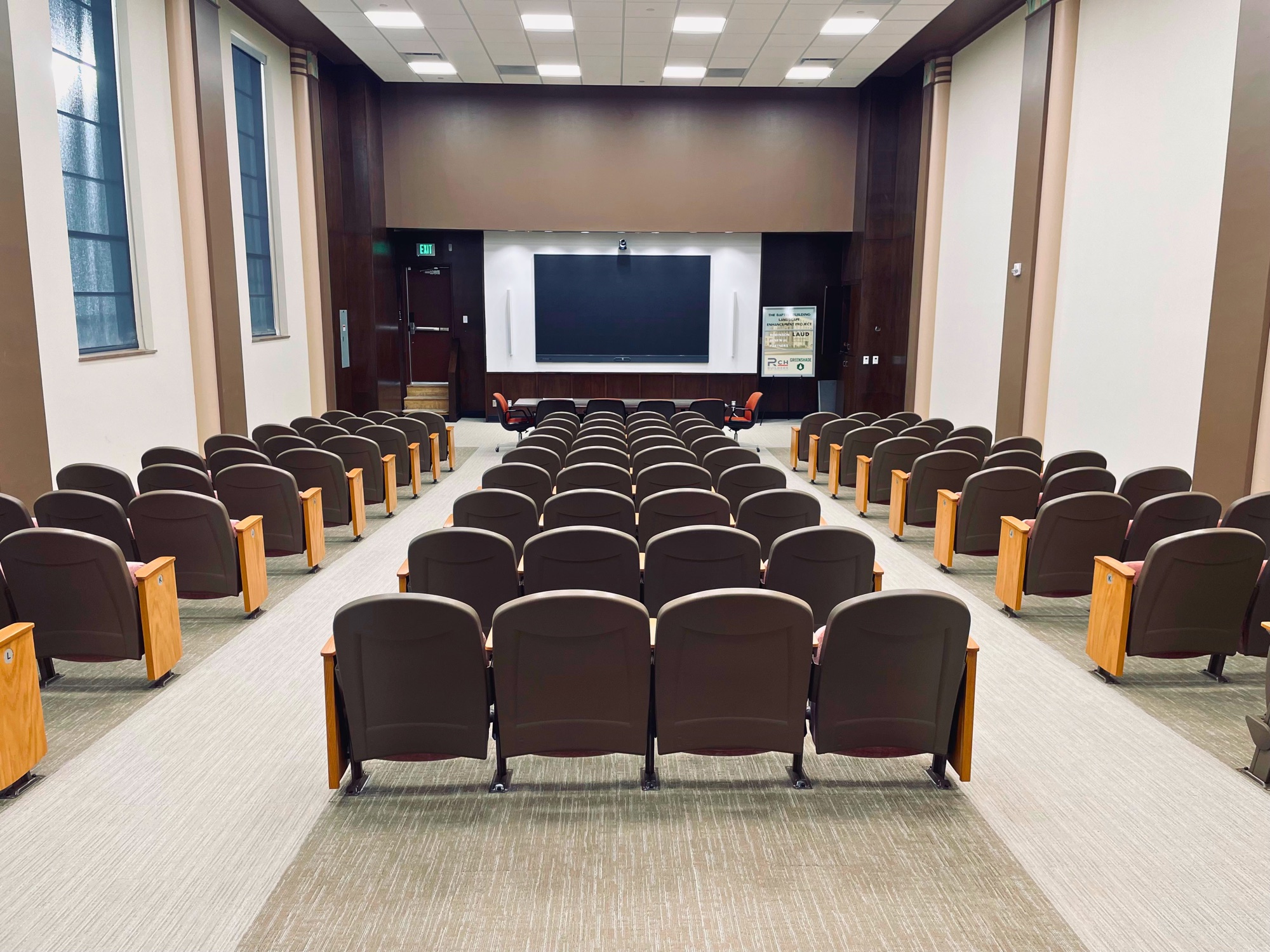 The 100+ seat auditorium at 1141 N Robinson, rows of fixed theater seating facing the 146-inch screen